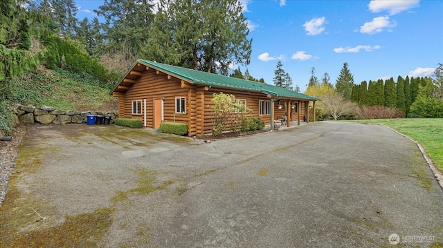 view of property exterior with log siding, metal roof, and driveway