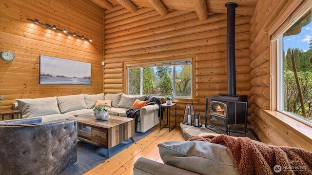 living area with a wood stove, beamed ceiling, wood-type flooring, and rustic walls