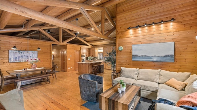 living room with beamed ceiling, wood walls, wooden ceiling, and light wood finished floors