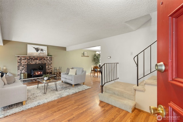 living room with light wood-type flooring, stairway, and a textured ceiling