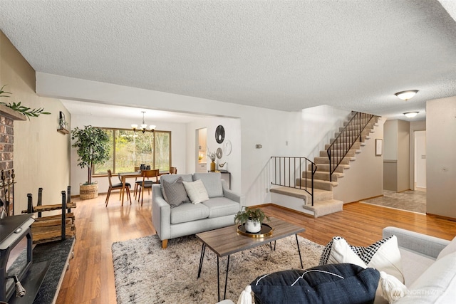 living area featuring wood finished floors, baseboards, stairs, a textured ceiling, and a chandelier