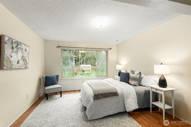 bedroom with wood finished floors, baseboards, and a textured ceiling