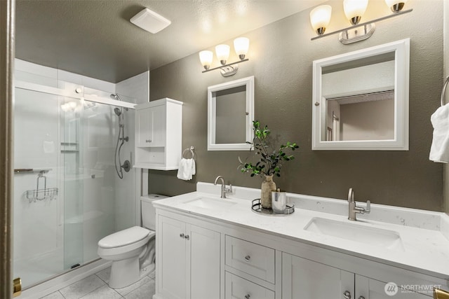 bathroom with double vanity, a shower stall, toilet, and a sink