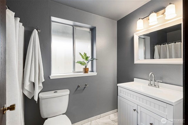 bathroom with vanity, toilet, baseboards, and marble finish floor