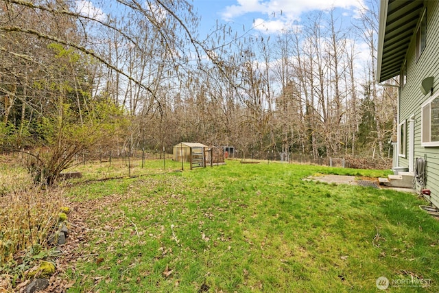 view of yard with entry steps, an outbuilding, and fence