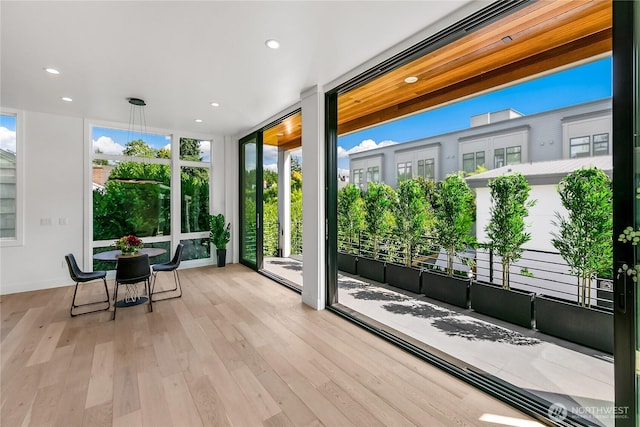 doorway to outside with a wall of windows, recessed lighting, and wood finished floors