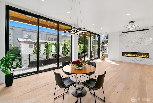 dining area featuring recessed lighting, wood finished floors, floor to ceiling windows, and a premium fireplace