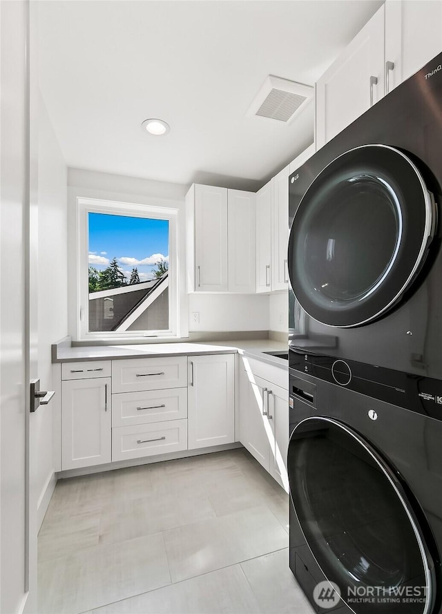 laundry room featuring visible vents, stacked washer and dryer, cabinet space, and recessed lighting