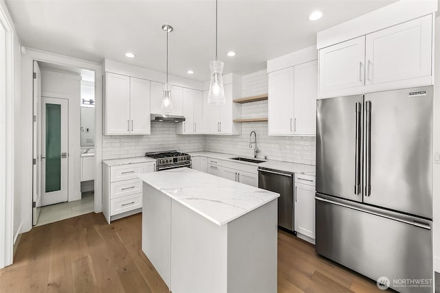 kitchen with a kitchen island, appliances with stainless steel finishes, under cabinet range hood, open shelves, and a sink