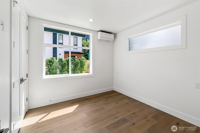 spare room with recessed lighting, wood-type flooring, a wall unit AC, and baseboards