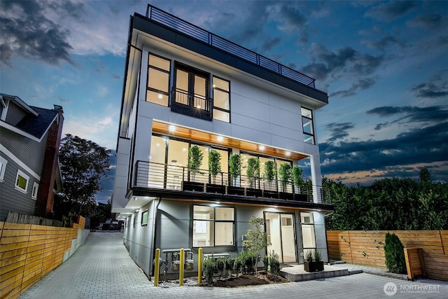 view of front of property featuring a balcony, fence, and stucco siding