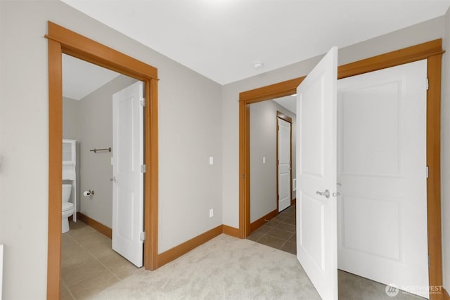 interior space featuring carpet flooring, baseboards, and tile patterned floors