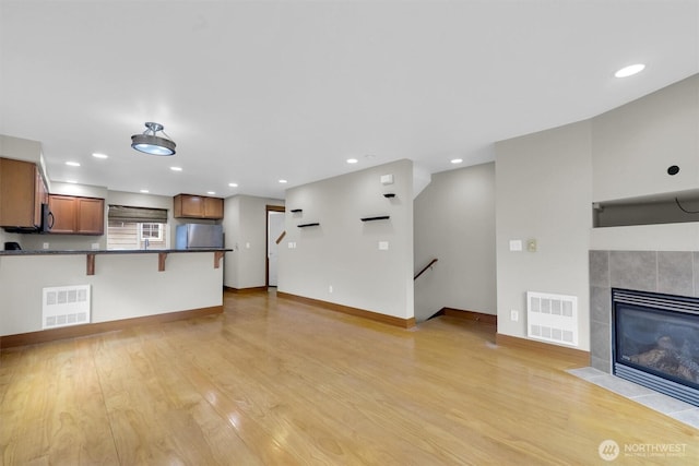 unfurnished living room with light wood-style floors, recessed lighting, visible vents, and a fireplace