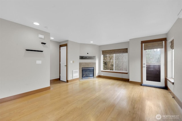 unfurnished living room with visible vents, baseboards, light wood-style flooring, a fireplace, and recessed lighting