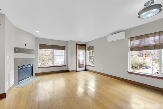 unfurnished living room with a tile fireplace, visible vents, baseboards, a wall mounted AC, and light wood finished floors