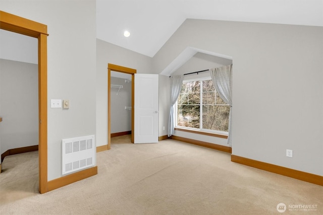 unfurnished bedroom featuring carpet floors, lofted ceiling, a walk in closet, and baseboards