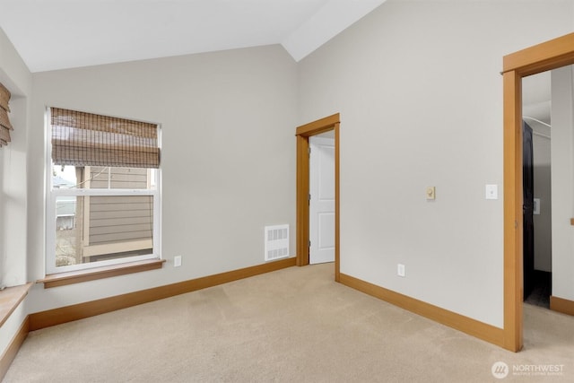 carpeted empty room with vaulted ceiling, visible vents, and baseboards