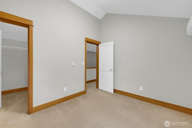 unfurnished bedroom featuring carpet floors, baseboards, vaulted ceiling, a closet, and a walk in closet