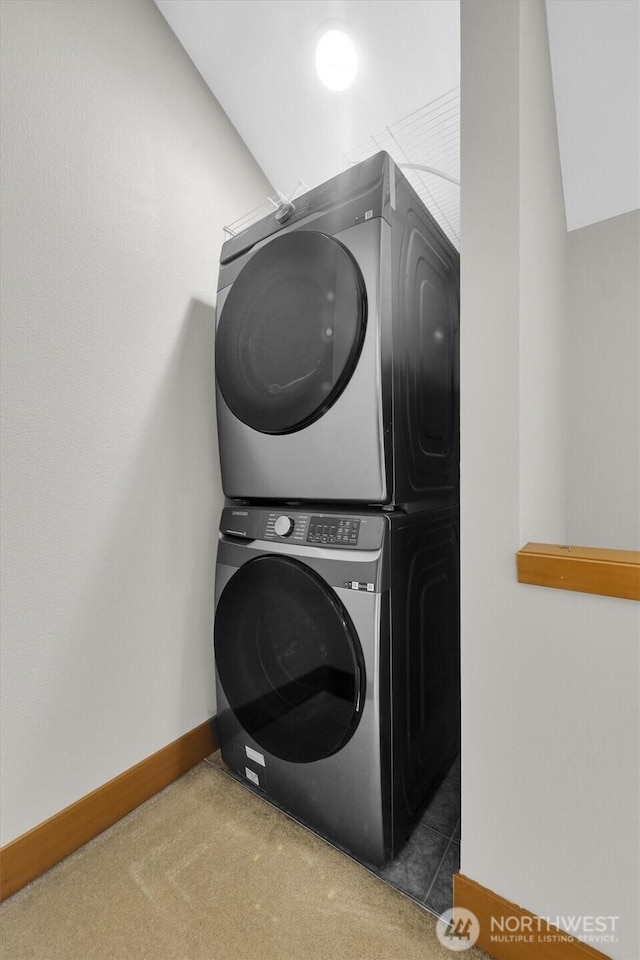 laundry area featuring carpet floors, stacked washer / dryer, laundry area, and baseboards