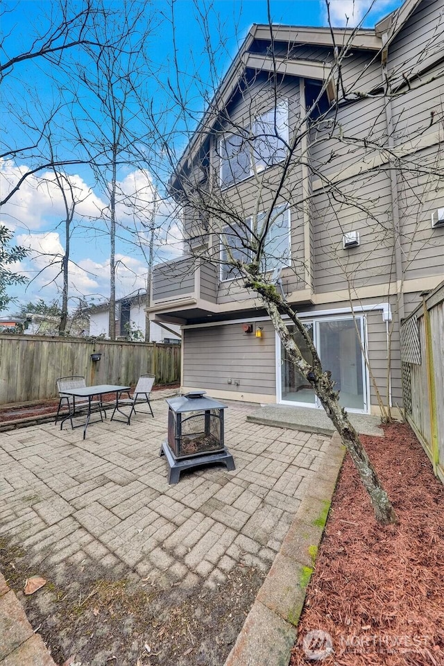 rear view of property with an outdoor fire pit, a fenced backyard, and a patio