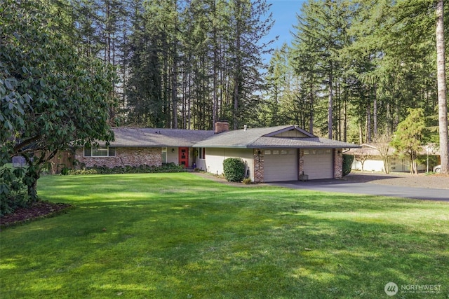 ranch-style home with a garage, brick siding, driveway, a front lawn, and a chimney