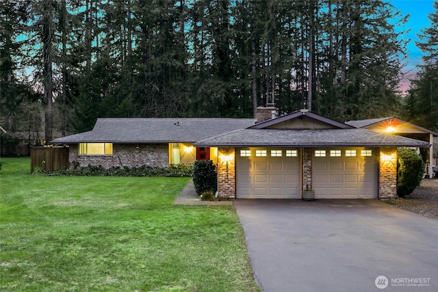 single story home featuring an attached garage, driveway, a shingled roof, and a front yard