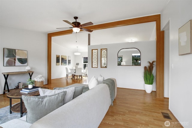 living area featuring vaulted ceiling, light wood-style floors, visible vents, and ceiling fan