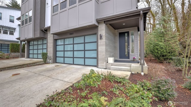 property entrance with a garage, driveway, board and batten siding, and brick siding