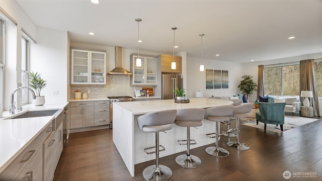 kitchen featuring a kitchen island, wall chimney range hood, appliances with stainless steel finishes, decorative backsplash, and dark wood finished floors