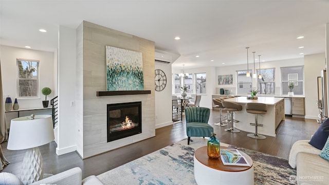 living area with recessed lighting, a fireplace, dark wood-type flooring, and a wall mounted air conditioner