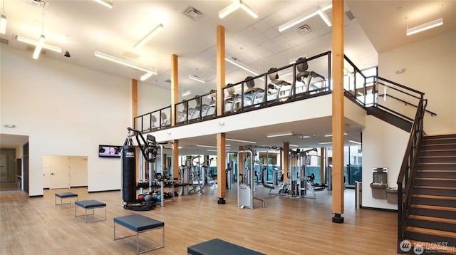 exercise room with visible vents, a high ceiling, and wood finished floors