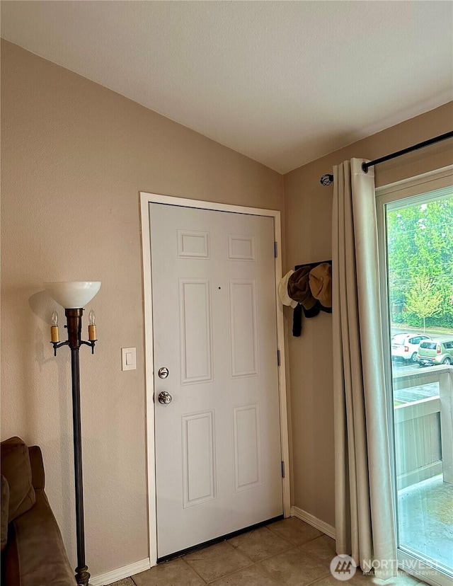 entryway featuring vaulted ceiling, baseboards, and light tile patterned floors