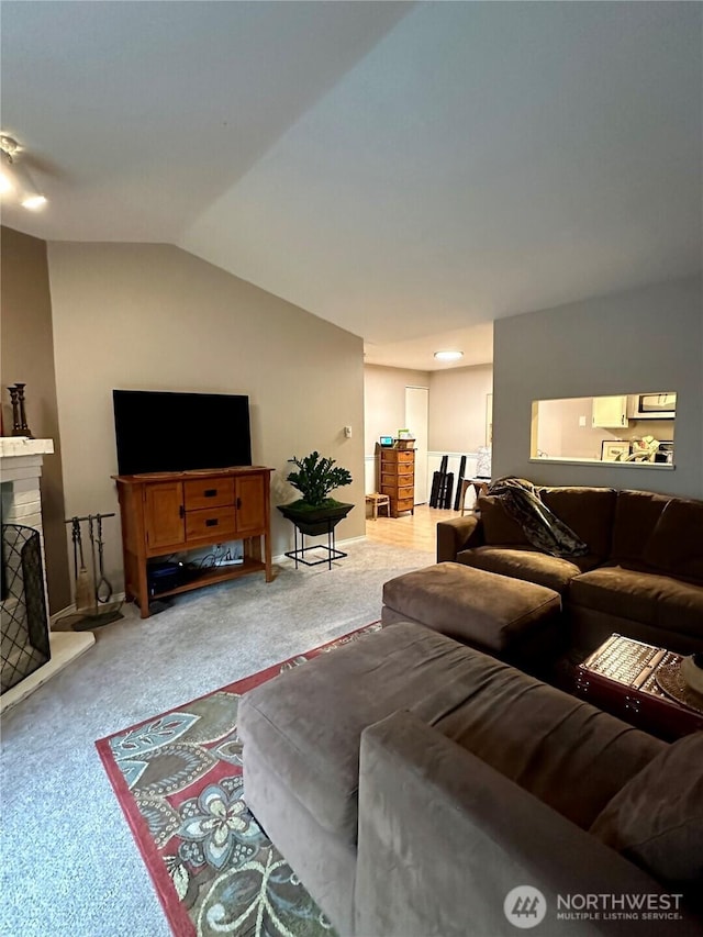 living area featuring a fireplace with raised hearth, carpet, and lofted ceiling