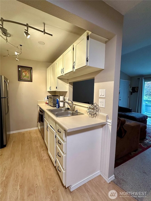 kitchen featuring light wood finished floors, appliances with stainless steel finishes, white cabinets, and a sink