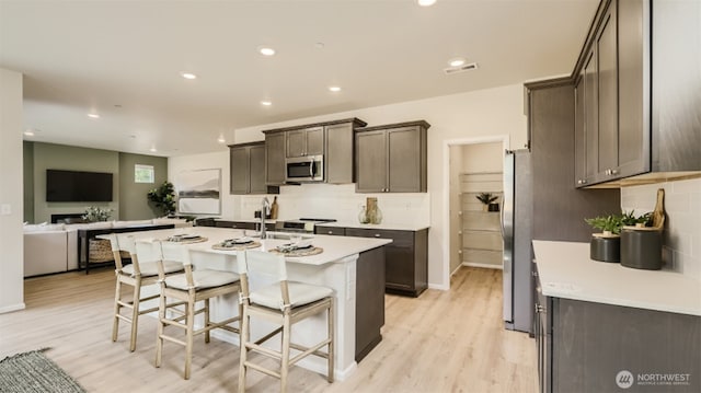 kitchen featuring a breakfast bar area, stainless steel appliances, tasteful backsplash, light countertops, and a sink