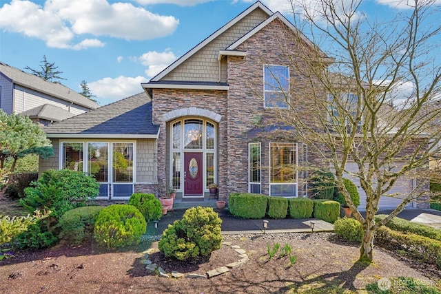 view of front of property featuring stone siding and roof with shingles