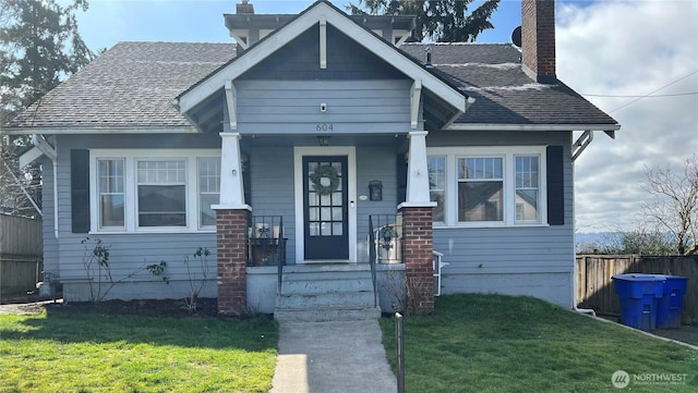 bungalow with a front yard, fence, and a chimney