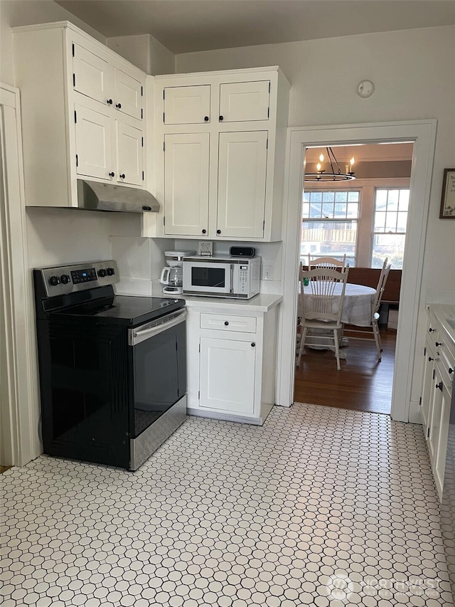 kitchen featuring stainless steel electric range oven, white microwave, light countertops, white cabinets, and under cabinet range hood