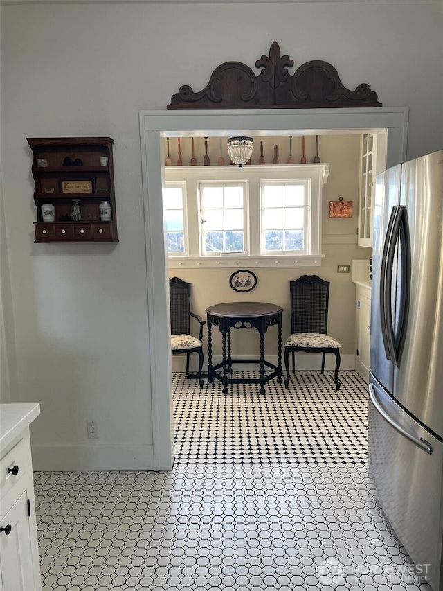 kitchen featuring white cabinetry, freestanding refrigerator, baseboards, and light countertops