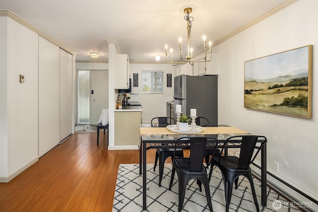 dining space featuring a notable chandelier, wood finished floors, and ornamental molding