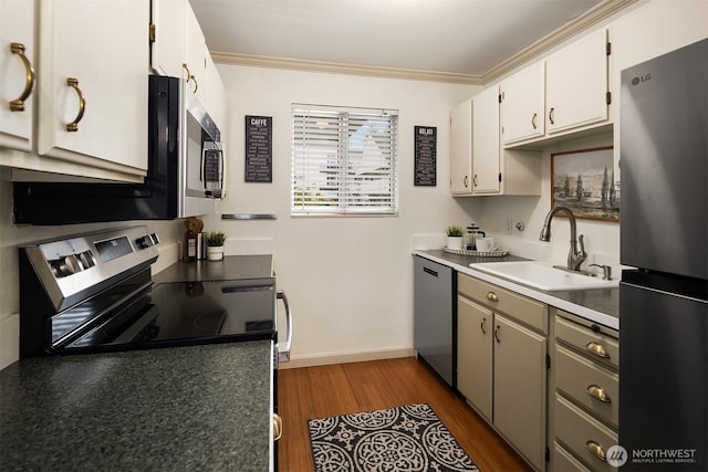 kitchen with crown molding, baseboards, dark wood finished floors, appliances with stainless steel finishes, and a sink