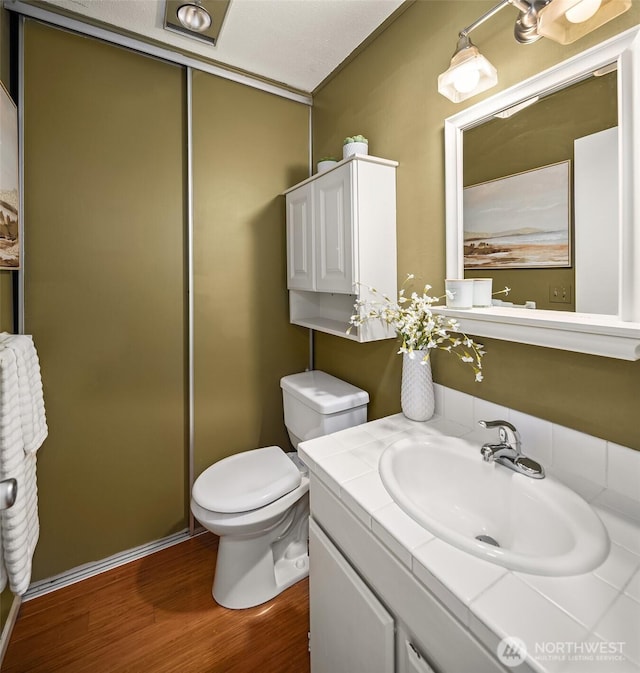 bathroom featuring toilet, wood finished floors, and vanity