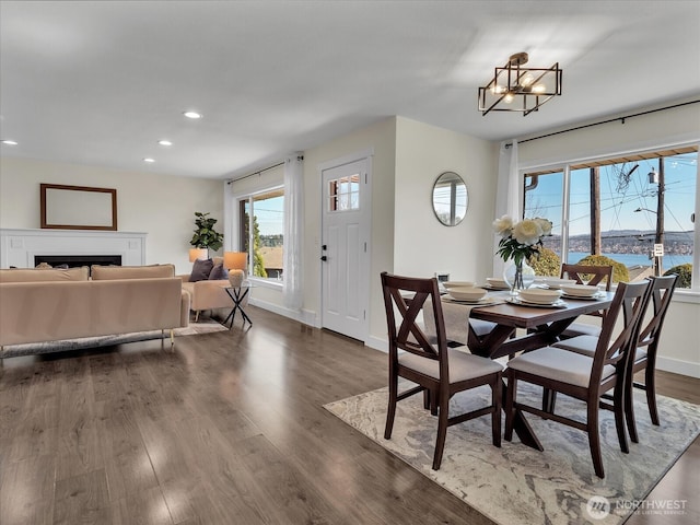 dining area with dark wood-style flooring, a fireplace, recessed lighting, a chandelier, and baseboards