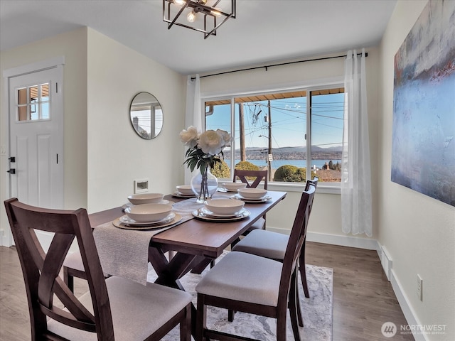 dining room with a chandelier, a water view, wood finished floors, and baseboards