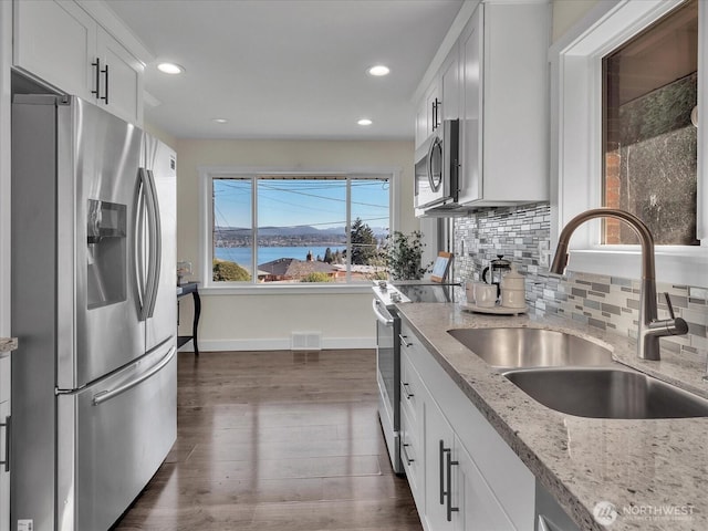 kitchen featuring tasteful backsplash, visible vents, dark wood finished floors, appliances with stainless steel finishes, and a sink