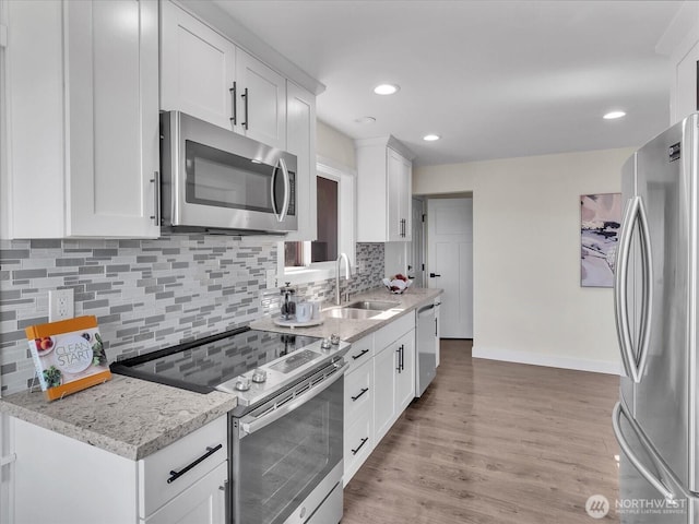 kitchen featuring light wood-style floors, white cabinetry, stainless steel appliances, and a sink