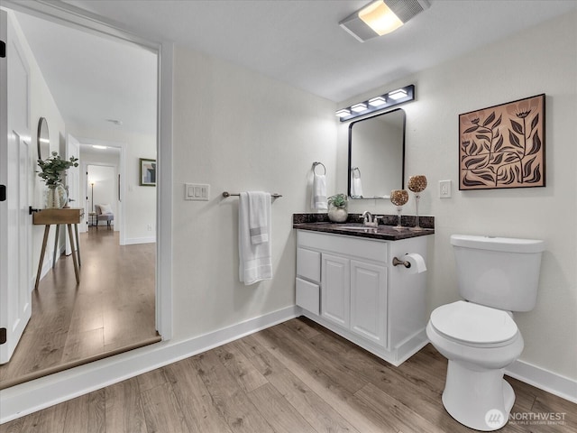 bathroom featuring vanity, wood finished floors, toilet, and baseboards