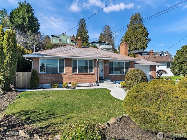 view of front of property featuring a front lawn, fence, and brick siding