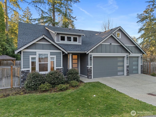 craftsman-style house featuring concrete driveway, stone siding, roof with shingles, fence, and board and batten siding