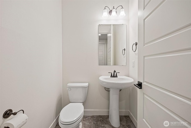 half bathroom with a sink, toilet, and baseboards